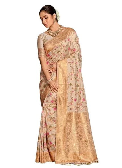 A woman dons the Soft Lightweight Traditional Banarasi Silk Saree 2025 in beige and gold, adorned with pink floral designs and intricate zari weaving, paired with a matching blouse and accessorized with gold jewelry and flowers in her hair.